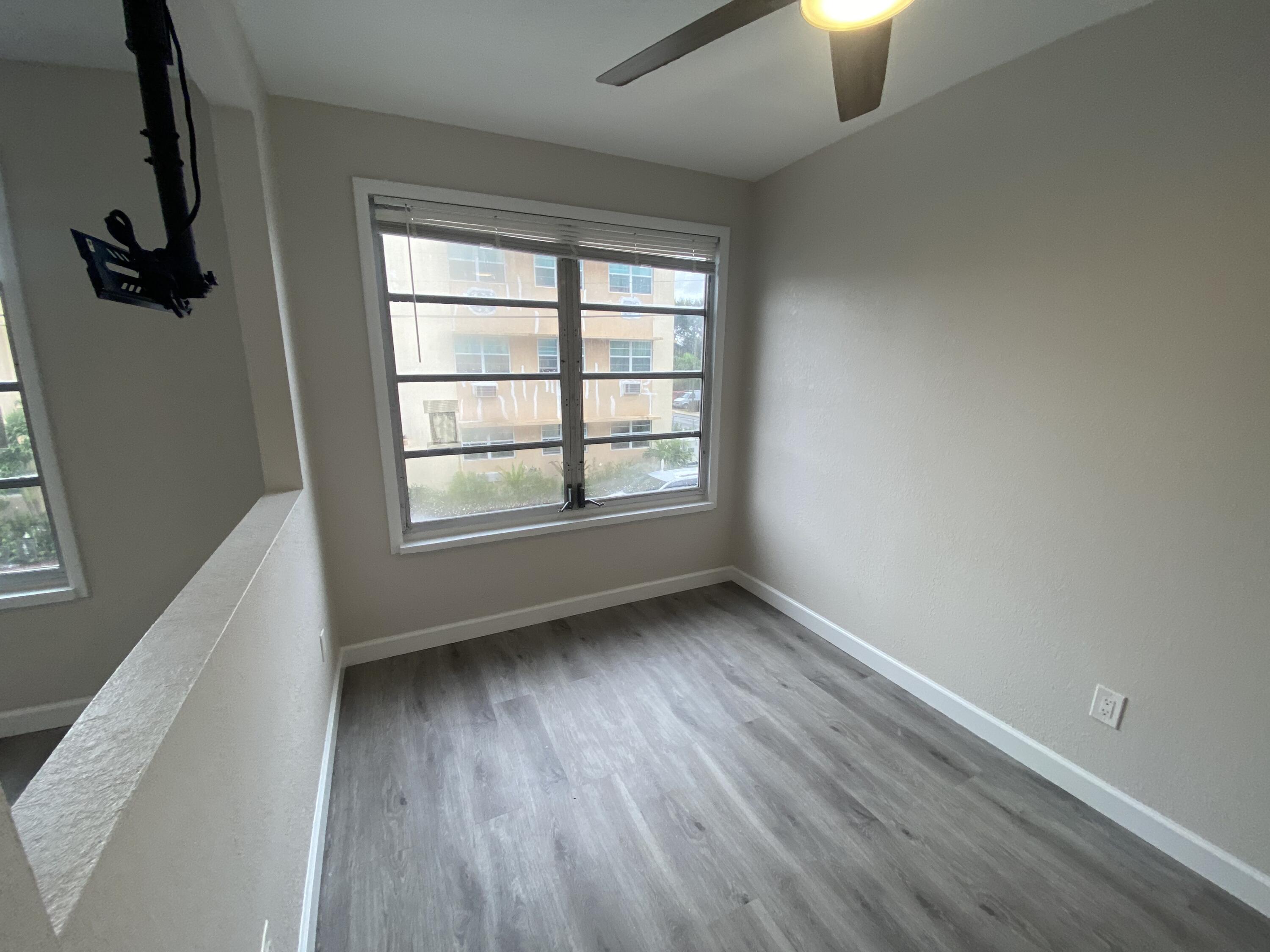 301 South M Street, Unit 5 Lake Worth Beach, FL 33460 - Photo 8 of 17 an empty room with wooden floor and windows