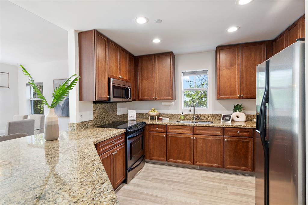 630 Southeast 15th Street, Unit 7 Fort Lauderdale, FL 33316 - Photo 6 of 21 a kitchen with stainless steel appliances granite countertop wooden cabinets a refrigerator a sink a stove a microwave and wooden floors