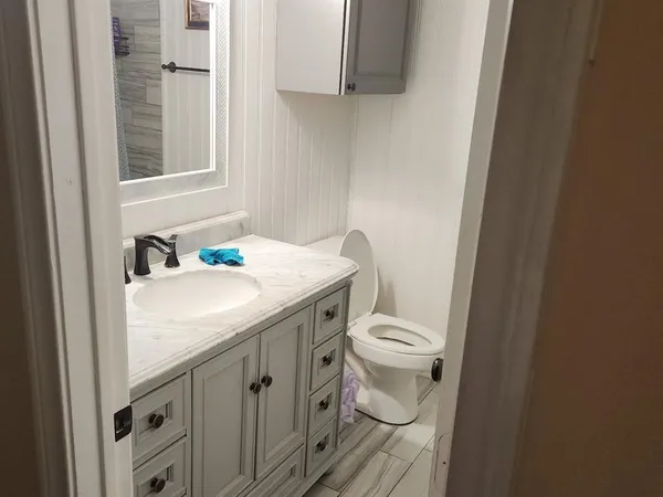 a bathroom with a granite countertop toilet sink and mirror