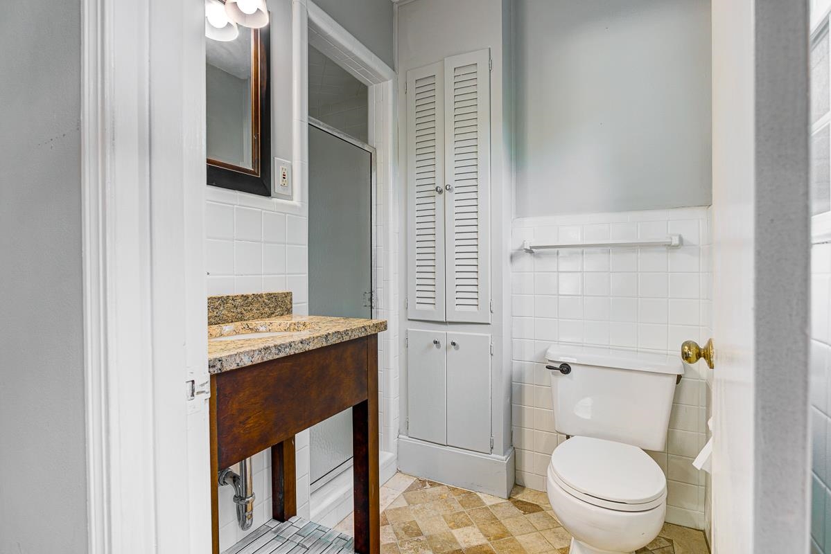 5676 Barfield Road Memphis, TN 38120 - Photo 15 of 19 Bathroom featuring a wood-finish vanity with a stone countertop, an integrated sink, and a framed mirror