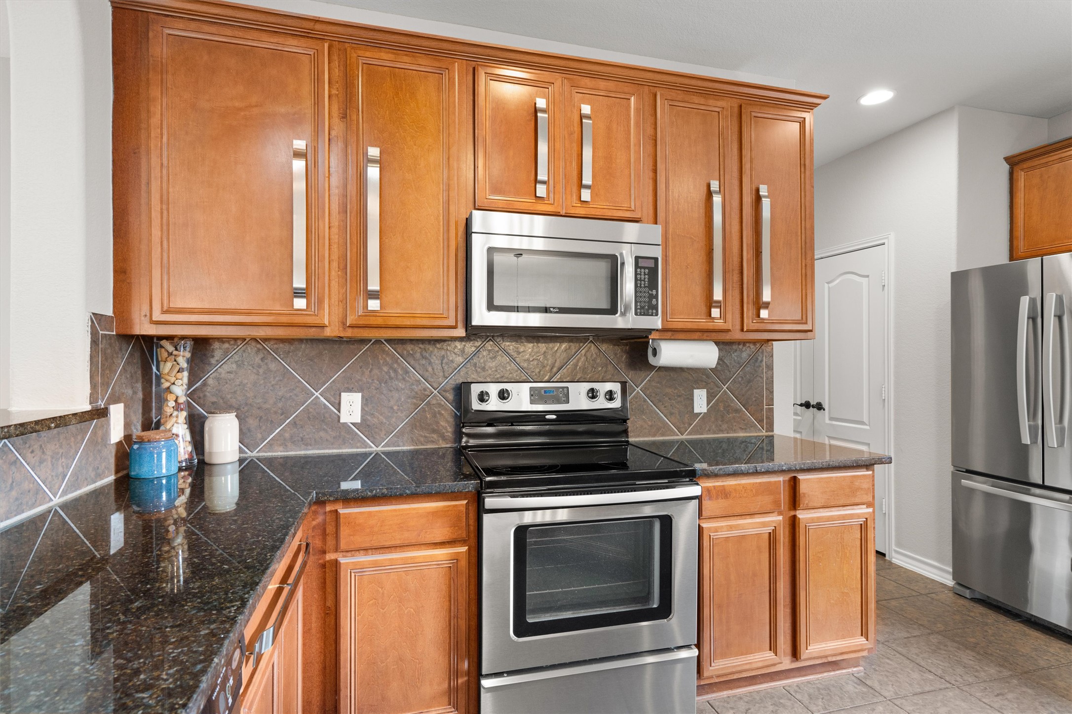 101 Breakaway Road Cedar Park, TX 78613 - Photo 13 of 37 Kitchen with stainless steel appliances, wood finish cabinetry, recessed lighting, tasteful backsplash, and light tile patterned floors
