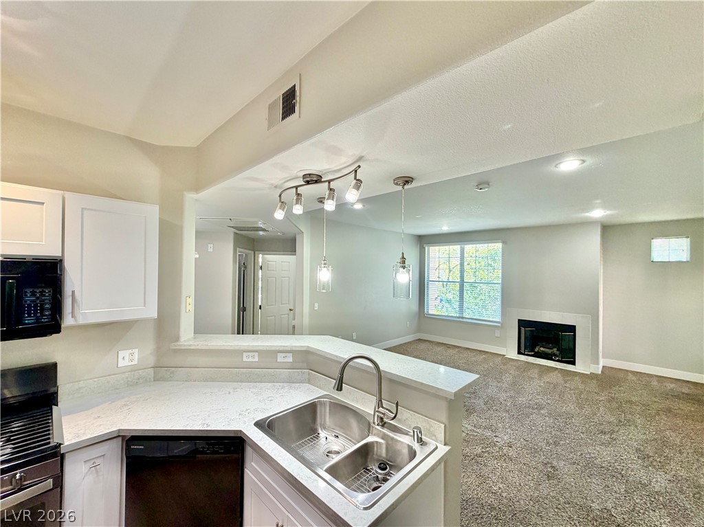 8555 West Russell Road, Unit 2018 Las Vegas, NV 89113 - Photo 23 of 23 A well-lit open floorplan connects a functional kitchen to a cozy living space featuring a fireplace.