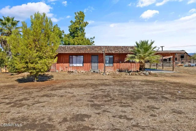 a front view of house with yard and trees in the background