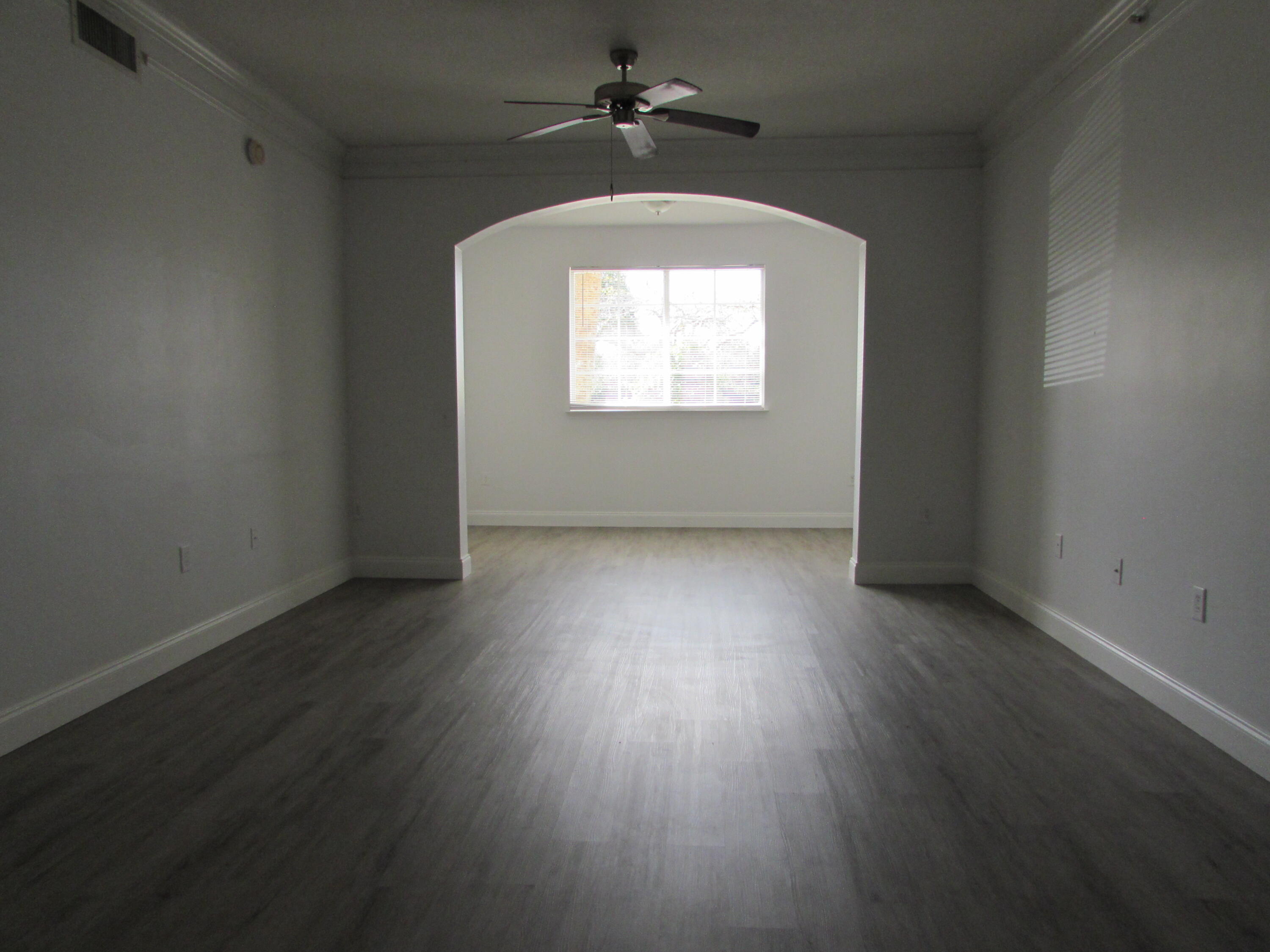 9873 Baywinds Boulevard, Unit 5107 West Palm Beach, FL 33411 - Photo 15 of 22 an empty room with wooden floor chandelier fan and windows