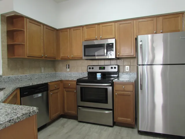 a kitchen with stainless steel appliances granite countertop a refrigerator stove a sink and a microwave