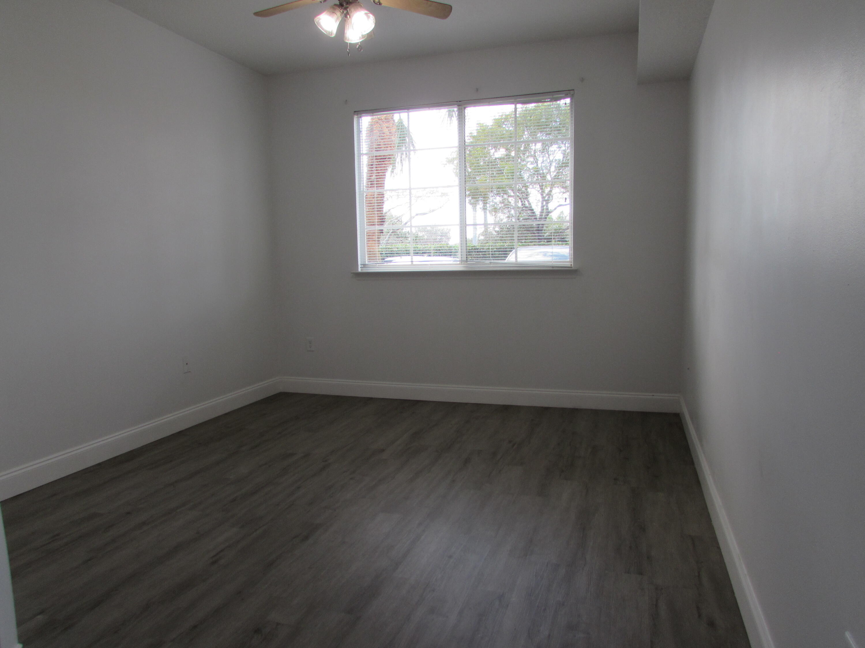 9873 Baywinds Boulevard, Unit 5107 West Palm Beach, FL 33411 - Photo 9 of 22 an empty room with wooden floor and windows
