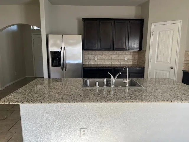 a kitchen with granite countertop a refrigerator a stove and cabinets