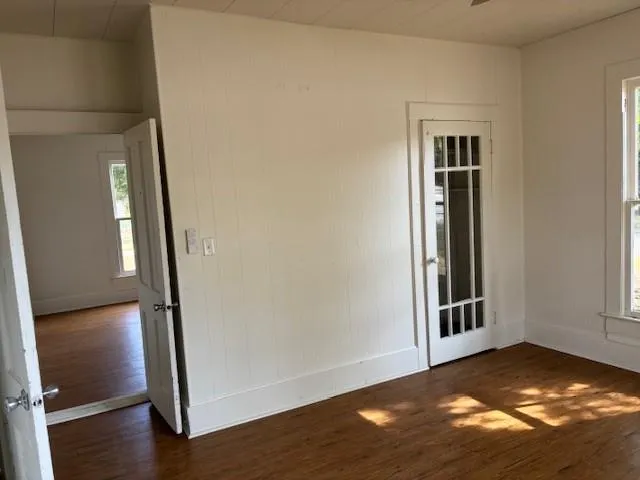 an empty room with wooden floor door and windows