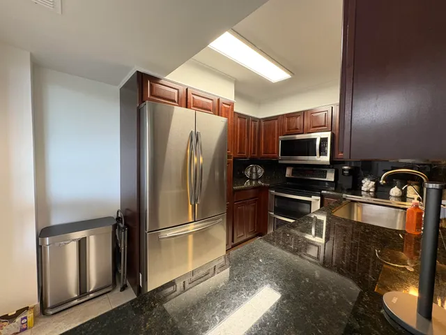 a kitchen with stainless steel appliances granite countertop a refrigerator a stove top oven a sink and dishwasher