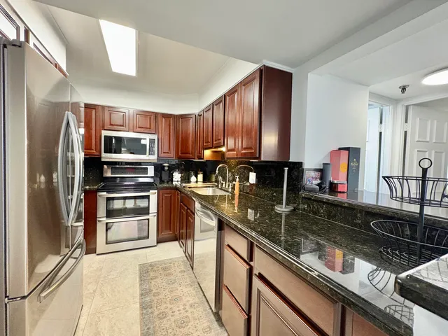 a kitchen with stainless steel appliances granite countertop a sink refrigerator and cabinets