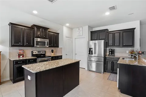a kitchen with kitchen island a refrigerator stove microwave and sink