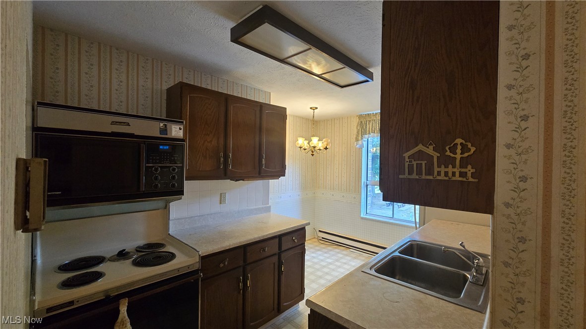 3068 Kent Road, Unit 210C Stow, OH 44224 - Photo 8 of 14 Kitchen featuring wallpapered walls, light countertops, dark brown cabinets, a chandelier, and a textured ceiling