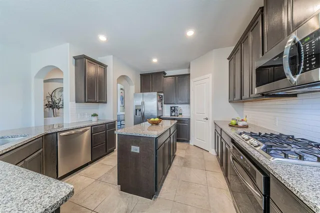 a kitchen with stainless steel appliances granite countertop a stove top oven a sink dishwasher and a refrigerator