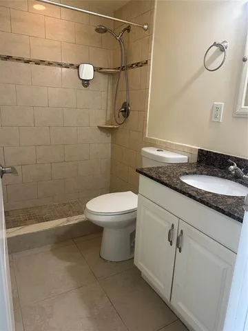 a bathroom with a granite countertop toilet a sink and shower
