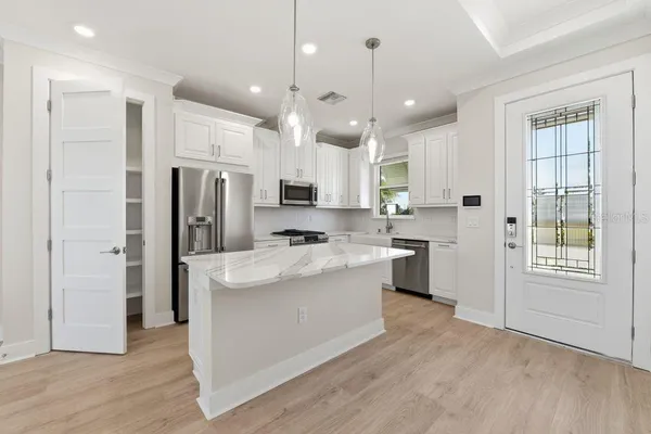 a large kitchen with a large counter top a sink stainless steel appliances and cabinets