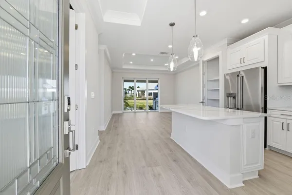 a large white kitchen with a refrigerator a sink and a large window