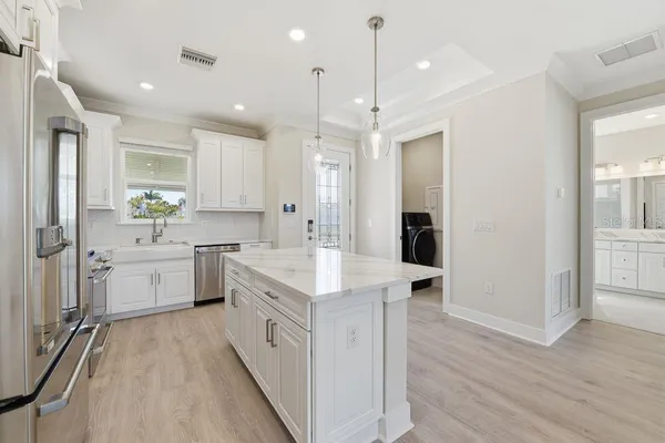 a large white kitchen with a stove a sink dishwasher and a refrigerator with wooden floor