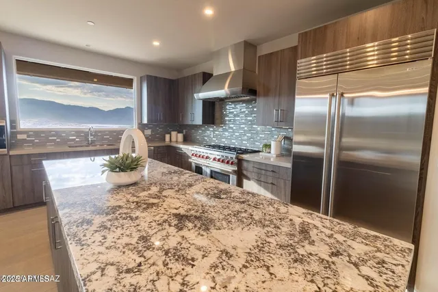 a kitchen with stainless steel appliances kitchen island granite countertop a refrigerator and a sink