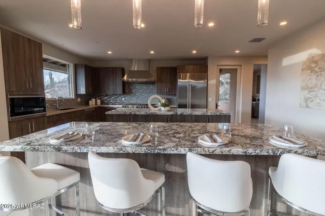 a kitchen with granite countertop kitchen island stainless steel appliances sink stove dining table and chairs