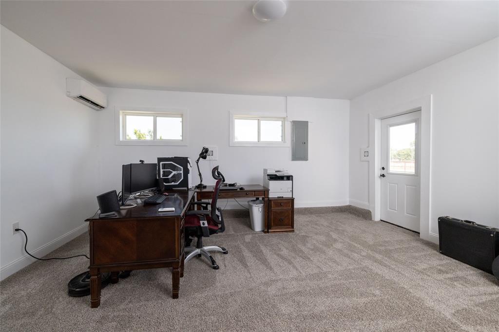 151 County Road 3699 Springtown, TX 76082 - Photo 25 of 35 Spacious room featuring neutral carpeting, white walls, multiple windows, a rear exterior door, and a wall-mounted mini-split HVAC unit