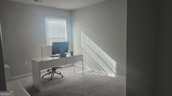 a view of a workspace with furniture and a window