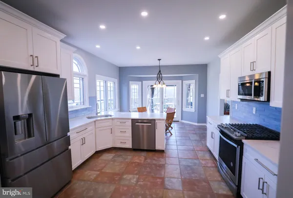 a large kitchen with stainless steel appliances kitchen island granite countertop a refrigerator and a stove top oven