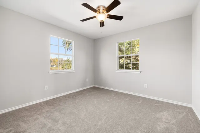an empty room with windows and fan