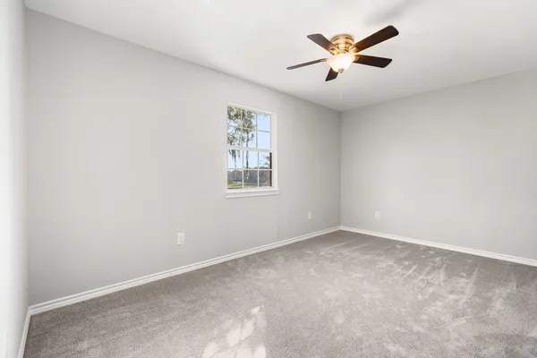 an empty room with window and a ceiling fan