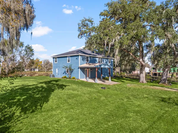 a view of a house with a big yard plants and large trees