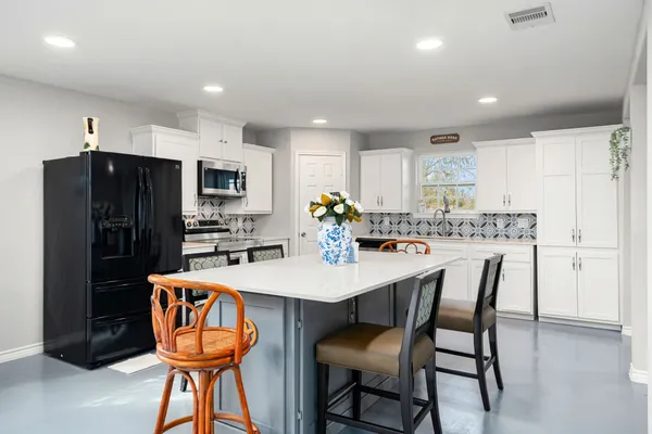 a kitchen with stainless steel appliances a dining table chairs refrigerator and microwave