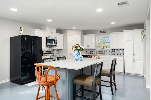 a kitchen with stainless steel appliances a dining table chairs refrigerator and microwave