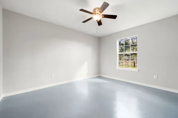 an empty room with a window and a fan