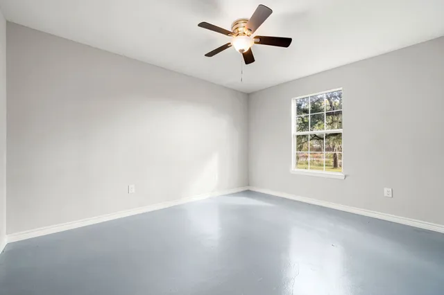 an empty room with a window and a fan
