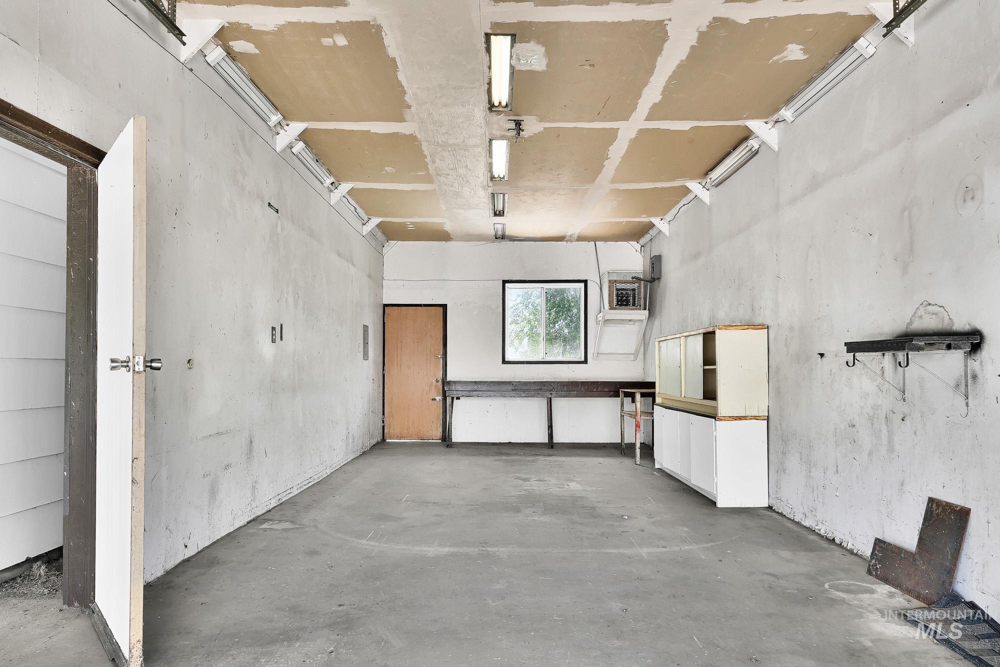5755 Chuckwagon Road Nampa, ID 83686 - Photo 37 of 50 Concrete floor garage with exposed ceiling joists, fluorescent lighting, and a single window