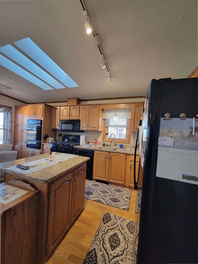 5016 West Colonial Drive, Unit 317 Monee, IL 60449 - Photo 12 of 32 a large kitchen with stainless steel appliances kitchen island granite countertop a refrigerator and a stove top oven