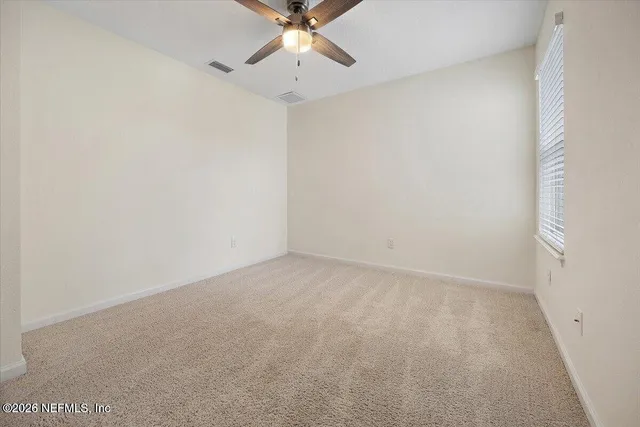 an empty room with a window and a fan