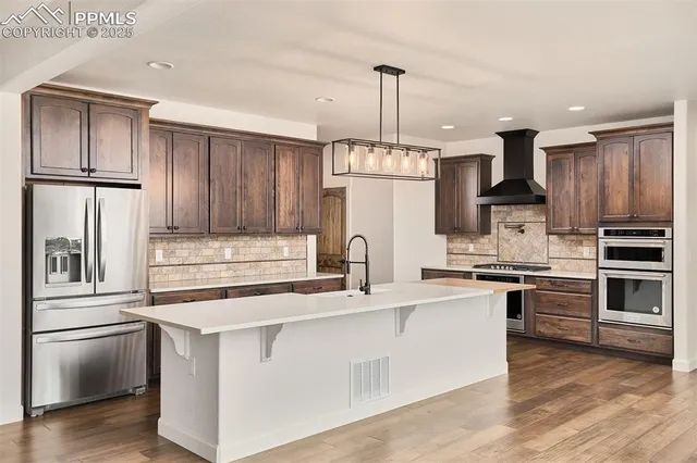 a kitchen with kitchen island granite countertop stainless steel appliances and refrigerator