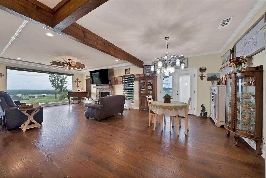 100 Shadle Ridge Court Poolville, TX 76487 - Photo 6 of 40 Spacious living area featuring wood-finish flooring, exposed wooden beams, and a stone-clad fireplace