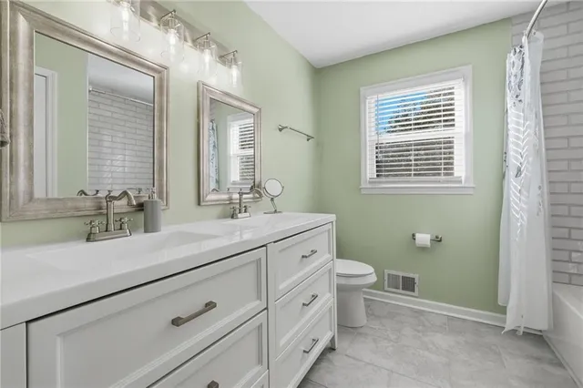a bathroom with a granite countertop toilet sink and mirror