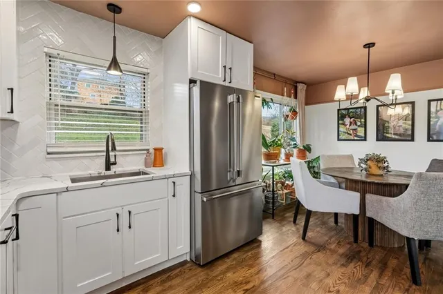 a kitchen with stainless steel appliances granite countertop a refrigerator a sink dishwasher a dining table and chairs with wooden floor