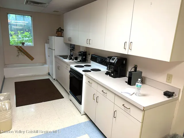 a kitchen with a sink a stove and white cabinets