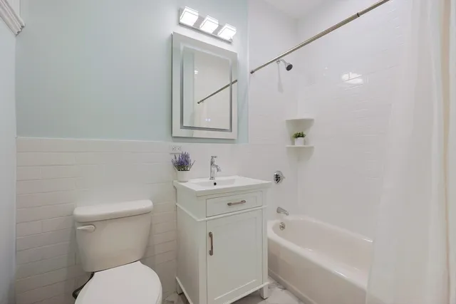a bathroom with a toilet a sink a mirror a bathtub and vanity