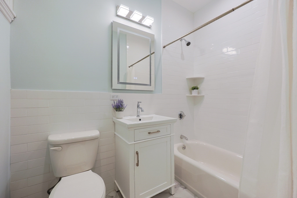 28 Inman Street, Unit 4 Cambridge, MA 02139 - Photo 25 of 32 a bathroom with a toilet a sink a mirror a bathtub and vanity