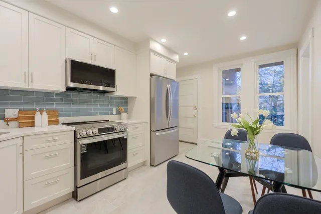 a kitchen with stainless steel appliances a stove a refrigerator a microwave a dining table and chairs with wooden floor