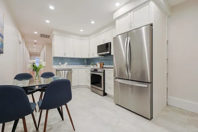 a kitchen with stainless steel appliances a refrigerator a stove a dining table and chairs