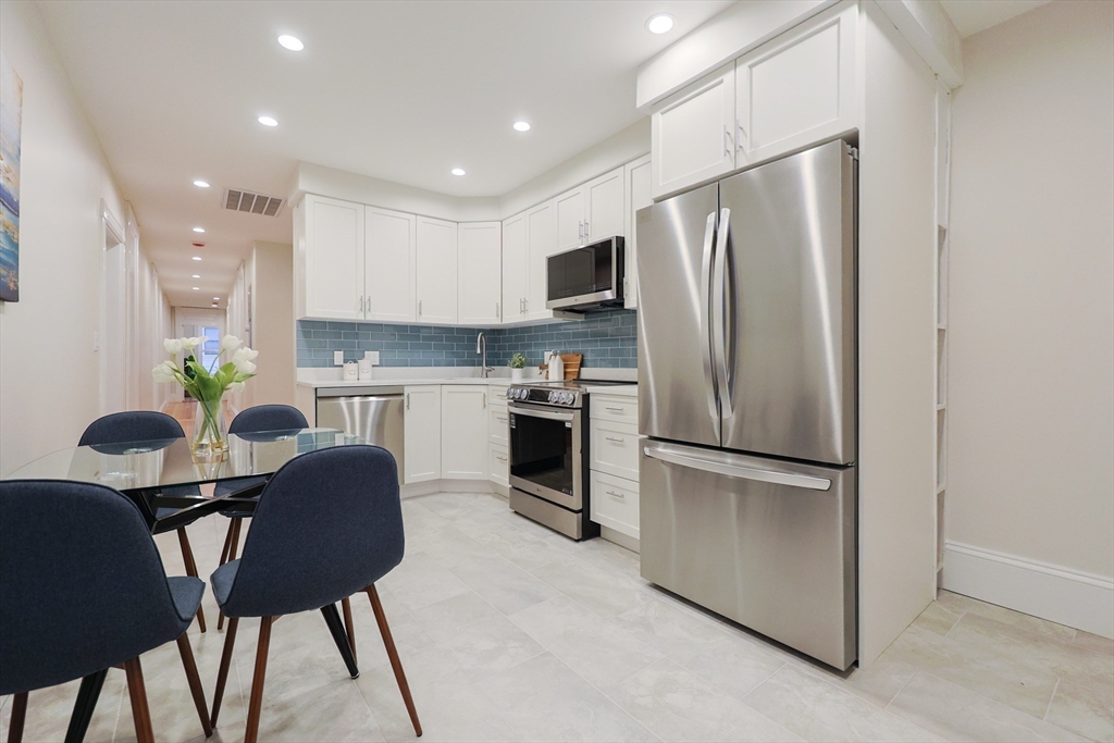 28 Inman Street, Unit 4 Cambridge, MA 02139 - Photo 8 of 32 a kitchen with stainless steel appliances a refrigerator a stove a dining table and chairs