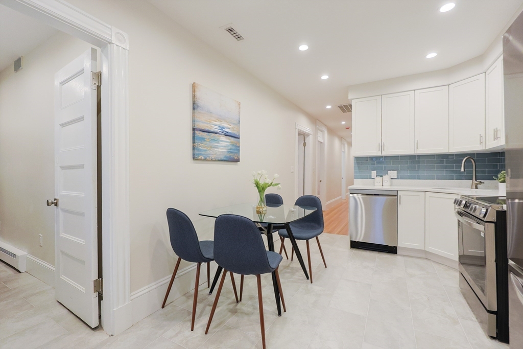 28 Inman Street, Unit 4 Cambridge, MA 02139 - Photo 9 of 32 a kitchen with a table chairs sink and cabinets