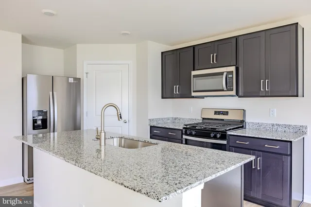 a kitchen with stainless steel appliances granite countertop a stove a sink and a microwave