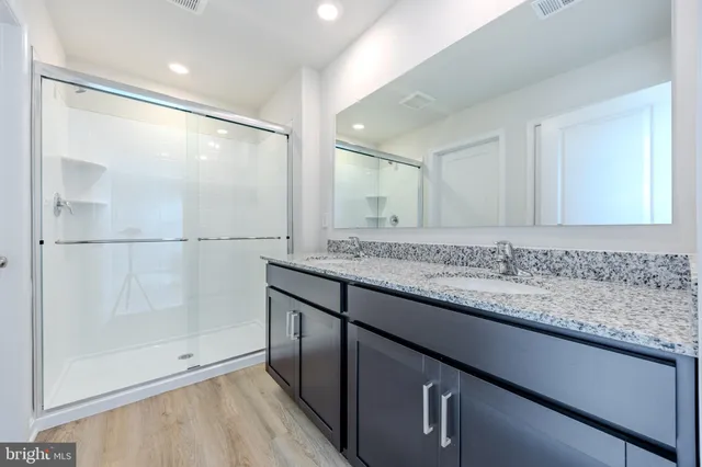 a bathroom with a granite countertop sink a mirror and a shower