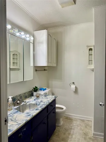 a bathroom with a granite countertop sink toilet and mirror